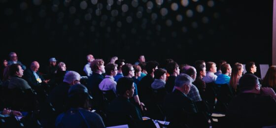 Photo of a crowd of people listening to a conference